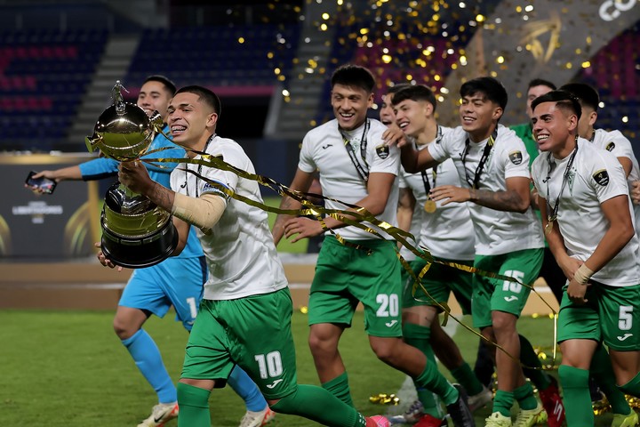 Lucas Avendaño (i) de Santiago Wanderers corre con el trofeo (EFE).